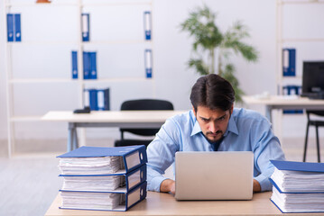 Young male employee and too much work in the office