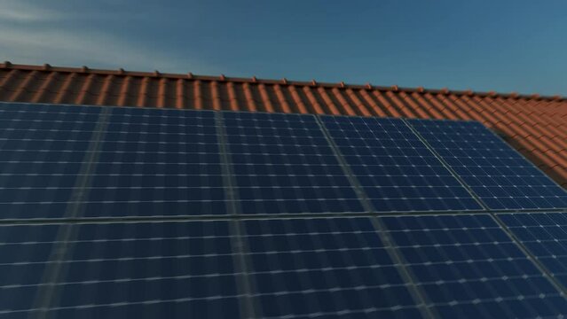 Solar panels modules on roof tiles at sunset. Sun reflecting on solar panels at dawn. 4k video panning on the rooftop of a residential house.