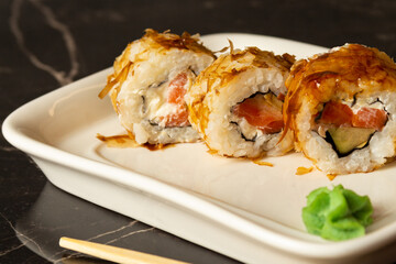sushi rolls of different varieties lie on a white tray on a dark background.