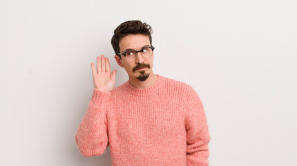 hispanic young man looking serious and curious, listening, trying to hear a secret conversation or...