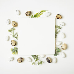 Fototapeta na wymiar Easter composition. Easter white and quail eggs, flowers, paper blank on toned white background. Flat lay, top view, copy space, mockup.