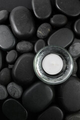 Spa stones  and candle on black background .