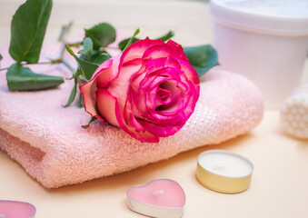 Rose and candles on a pink towel, the concept of a spa evening at a hotel, at a resort. Bathroom accessories.