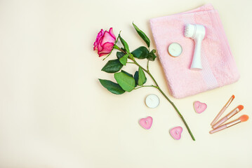 Rose and accessories for women's cosmetic procedures on a beige background. Spa hotel, salon as a gift. Flat lay. Copy space.