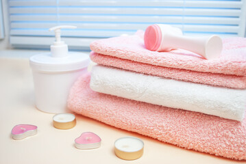 Accessories for women's salon spa treatments, towels, candles, lotion. Pastel white and pink tones. Hotel.