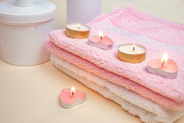 Burning candles on pink and white towels. Accessories for spa treatments in the salon, hotel. Focus concept. Bluering.