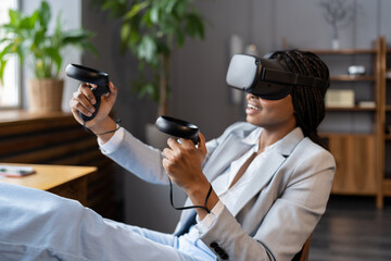 Young excited african american woman wearing vr glasses hold remote joystick first experience of...