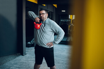 Middle aged men exercising at the gym while using kettlebell