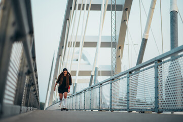 Young woman riding her longboard on the bridge