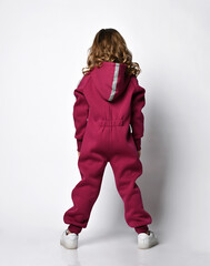 cool girl with curls in a burgundy hooded jumpsuit with reflective safety stripes, standing with...