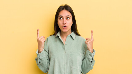 young hispanic woman feeling awed and open mouthed pointing upwards with a shocked and surprised...