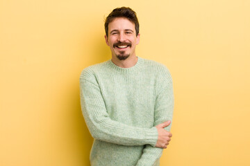 young hispanic man laughing shyly and cheerfully, with a friendly and positive but insecure attitude