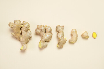 Fresh ginger root chopped ginger pieces on beige background top view flat lay. Spice for cooking,...
