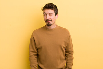 young hispanic man looking happy and friendly, smiling and winking an eye at you with a positive...
