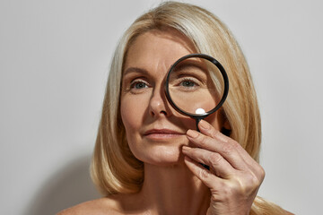 Mature woman looking away through magnifying glass