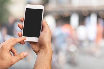 Human hand holding phone with blank screen and cityscape blur background