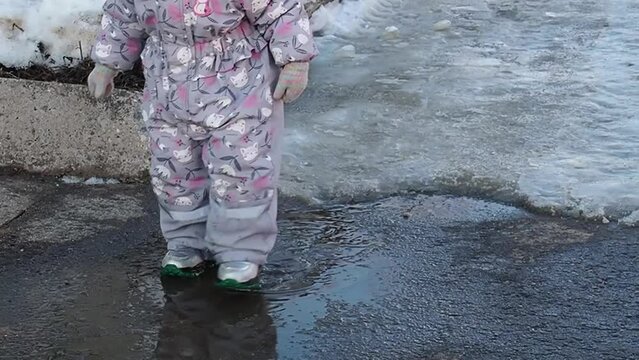 children run through the puddles in the spring on a sunny day