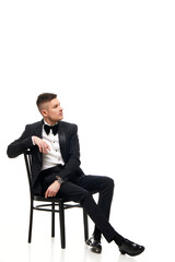 handsome man in tuxedo sitting on chair