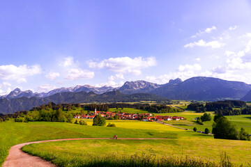 Fototapeta premium Family walking down a hiking path to the Village Zell with view on the Alps in Bavaria