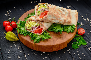 Fresh tortilla wrap with vegetables and salmon on wooden cutting board