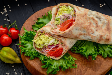 Fresh tortilla wrap with vegetables and salmon on wooden cutting board