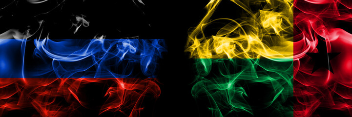 Fototapeta premium Donetsk People's Republic vs Guinea Bissau flag. Smoke flags placed side by side isolated on black background.