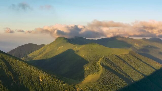 Time lapse Clouds over green mountain range in spring nature at sunrise