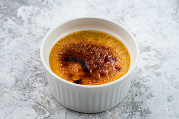 Single bowl of creme brulee. Burned cream with caramelized brown sugar in a ramekin bowl
