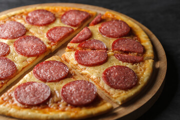 Pepperoni pizza cut into conical pieces on wooden stand, selective focus.
