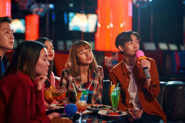 Group of young asian people enjoying at karaoke nightclub