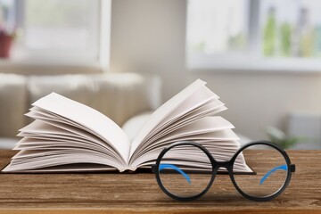Reading book at home. Opened paper pages and spectacles at home