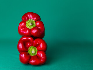 Two red peppers on a cyan green background