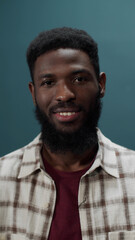 Obraz premium Carefree stylish dark-skinned young guy posing in checkered shirt isolated in a green studio
