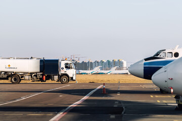 Fototapeta na wymiar Side view small modern fuel tanker truck driving on airfield taxiway for aircraft refueling. Cistern lorry aviation gasoline. Plane gas supply. Airport maintenance handling service vehicle equipment