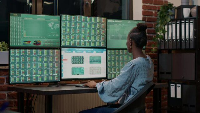 Fund trader working with real time stocks on multi monitors, looking at market exchange statistics and numbers. Trade sales investment graphs to plan new selling strategy. Tripod shot