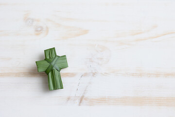 Isolated palm leaf cross on a white wood background with  copy space