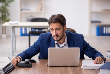 Young male employee unhappy with excessive work in the office