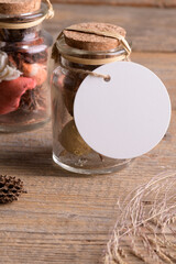 Round white tag mockup on glass jars with dry perfume a wooden background with boho decoration, element for packing. Label product mockup and natural eco design. Bohemian wedding gift, wedding favors