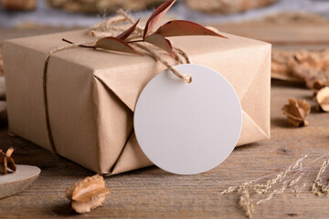Round white gift tag mockup on Christmas or Valentines Day wrapped presents on rustic wooden background with boho decoration. Spring blank label product mockup of bohemian mockup