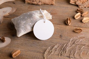 Round white gift tag mockup on gift packet on rustic wooden background with boho decoration. Spring...