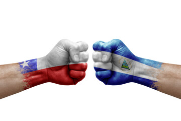 Two hands punch to each others on white background. Country flags painted fists, conflict crisis concept between chile and nicaragua