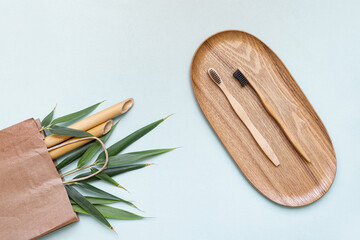 Bamboo toothbrush and eco bag on a table with copy space on a blue background. Styled composition of flat lay with bamboo leaves .