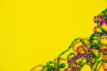 Mardi Gras concept. Multicolored beads on yellow background. Festive carnival symbols.