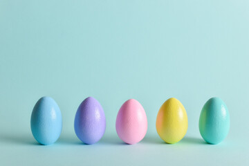 Painted eggs of delicate tones stand on a pale blue background.