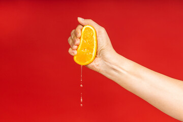 Orange fruit in woman's hand isolated over red background. Hand crushing fresh juice. - 488886944