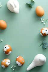 Easter flat lay vertical composition. Easter eggs, flowers, Easter bunny on pastel green background.