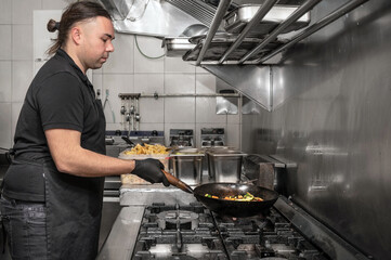 Side view of male chef working in commercial kitchen. High quality photography