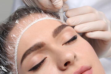 Young woman during procedure of permanent eyebrow makeup, closeup - obrazy, fototapety, plakaty