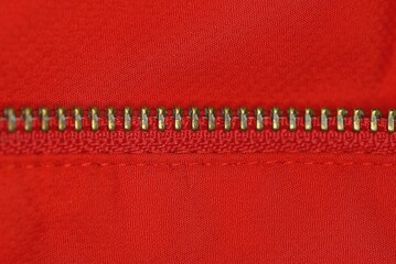 part of the yellow metal zip on the red fabric of the clothes © butus
