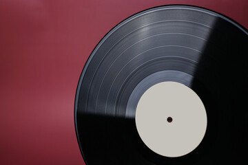 Classic vinyl record close-up on a red burgundy background, outdated data storage, music